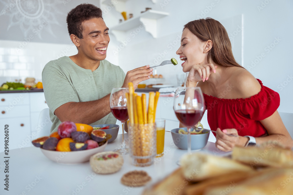 Cheerful international man feeding his pretty partner Cheerful international man feeding his pretty partner