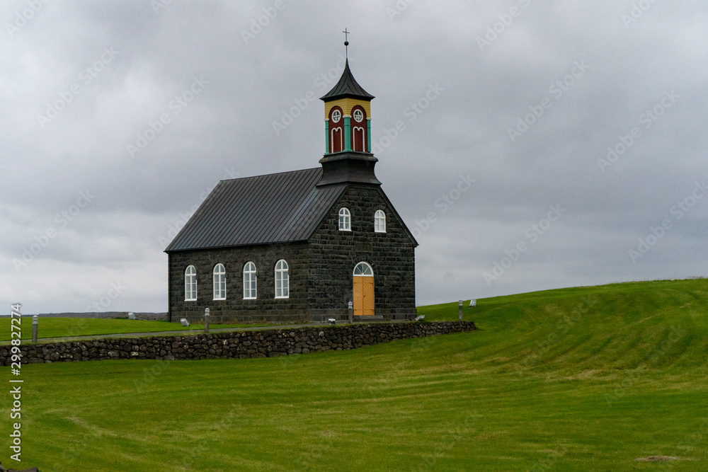 Black and colorful stone church on a hill