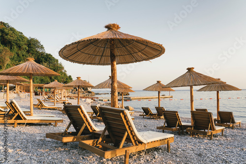 Fototapeta Naklejka Na Ścianę i Meble -  Pebble beach with hammocks and umbrellas at sunset in Jaz Beach, Montenegro.