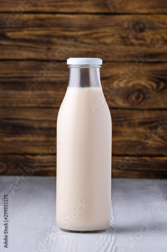 Bottle of soy milk on white table over dark wooden background