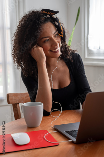 Shot of young latin woman working at home with laptop and documents