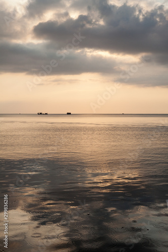 Calm sea at dawn a dramatic sky and raindrops on the sea surface and fishing boats in the distance, Koh Rong island, Cambodia. © Colleen Slater