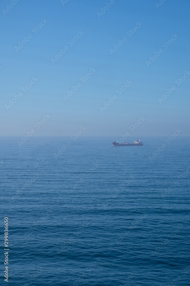 Cloudy horizon and Fog over the sea waves, natural background, red cargo ship on the horizon Cloudy horizon and Fog over the sea waves, natural background, red cargo ship on the horizon