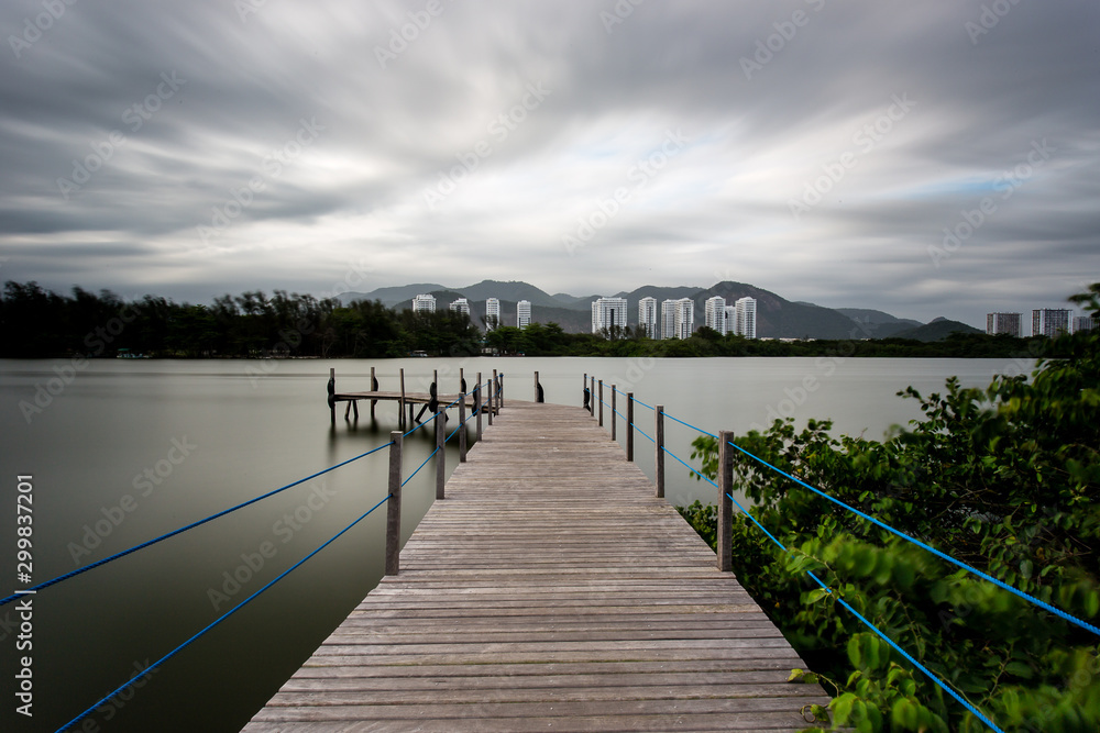 Long exposure of pier in calm lake, with nature all around, water is silky smooth