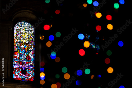 BELFAST, NORTHERN IRELAND, DECEMBER 19, 2018 Detail of a colorful stained glass window from inside of church, seen across a beautiful bokeh of christmas lights.