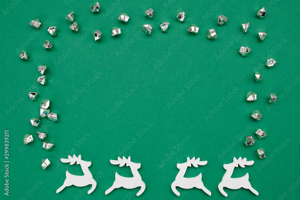 Fototapeta premium Christmas frame on dark green background with wooden handmade deers, decorations and copy space. Flat lay, top view, New Year banner mockup