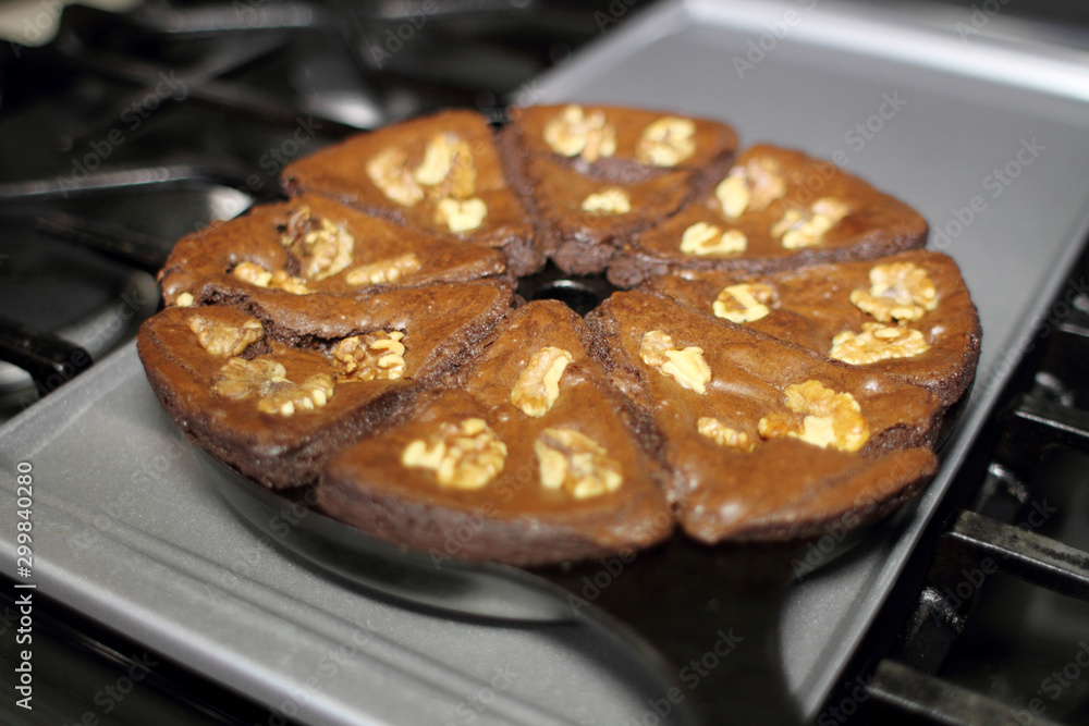 Φωτογραφία Chocolate brownies with walnuts baked in a cast iron wedge pan, resting on the stove top in a home kitchen