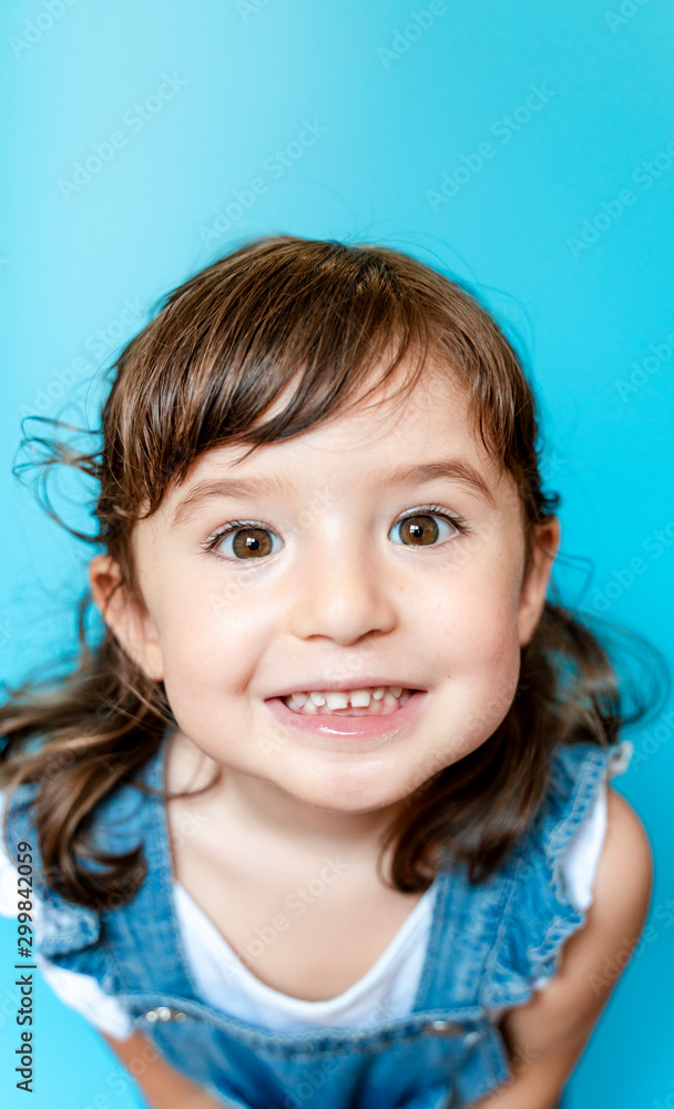 Portrait of cute little girl smiling very expressive on blue background Portrait of cute little girl smiling very expressive on blue background