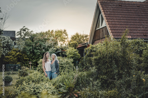 Mother and daughter standing in garden, inf ront of their house photo