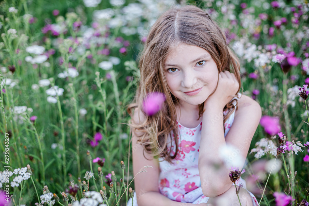 Portrait of smiling girl sitting on a flower meadow Portrait of smiling girl sitting on a flower meadow