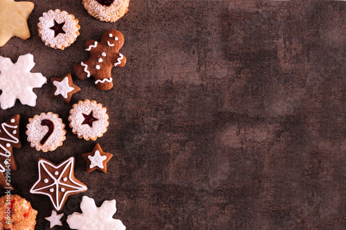 Selection of Christmas cookies and sweets. Above view side border over a dark stone background with copy space. Holiday baking concept.
