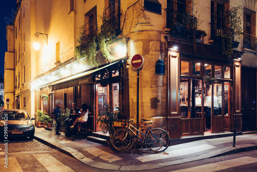 Night view of cozy street with tables of cafe and old bicycle in Paris, France © Ekaterina Belova