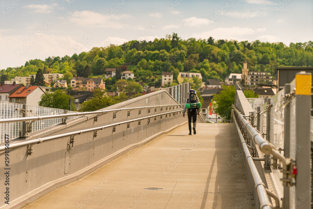 Wanderer geht über moderne Brücke im Sonnenschein