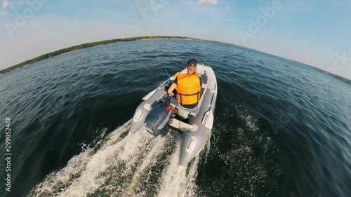 Backside view of a man in a lifevest navigating the autoboat photo