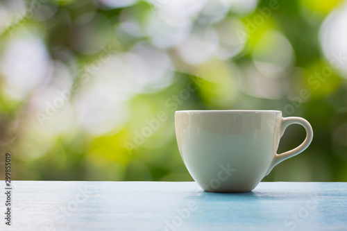 Close up coffee cup on blue wooden table with nature on background