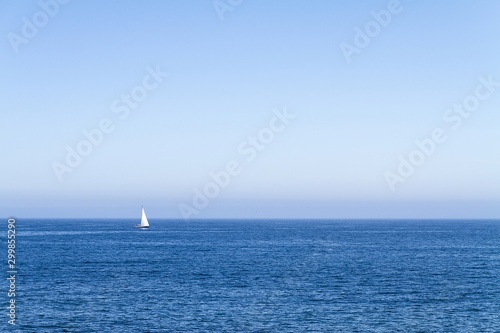 White boat floating in the horizon of a calm ocean