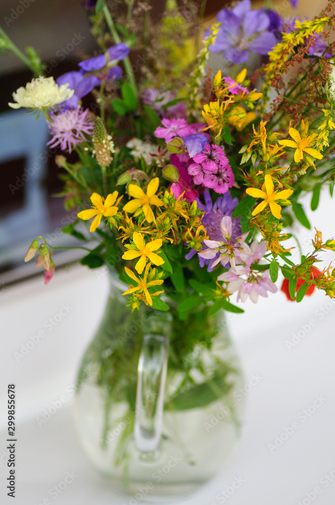 Beautiful bouquet of bright wildflowers in glass vase