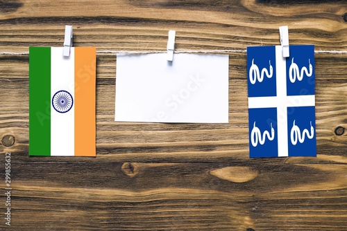 Hanging flags of India and Martinique attached to rope with clothes pins with copy space on white note paper on wooden background.Diplomatic relations between countries.
