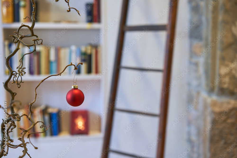 Red christmas ball in foreground in cozy loft with book shelf