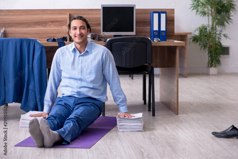 Young handsome businessman doing exercises at workplace Young handsome businessman doing exercises at workplace