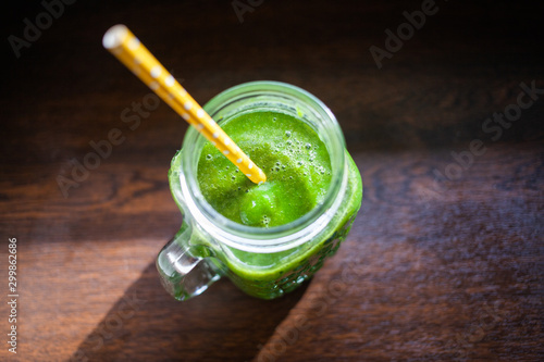 jar with green cold-pressed juice, wooden background. Healthy eating, detoxing, juicing, body cleancing concept photo