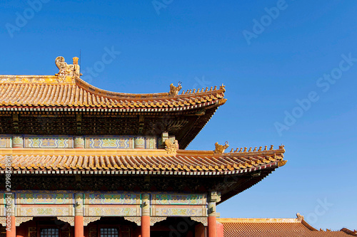 curved roofs in traditional Chinese style with figures on the blue sky background. The Imperial Palace in Beijing