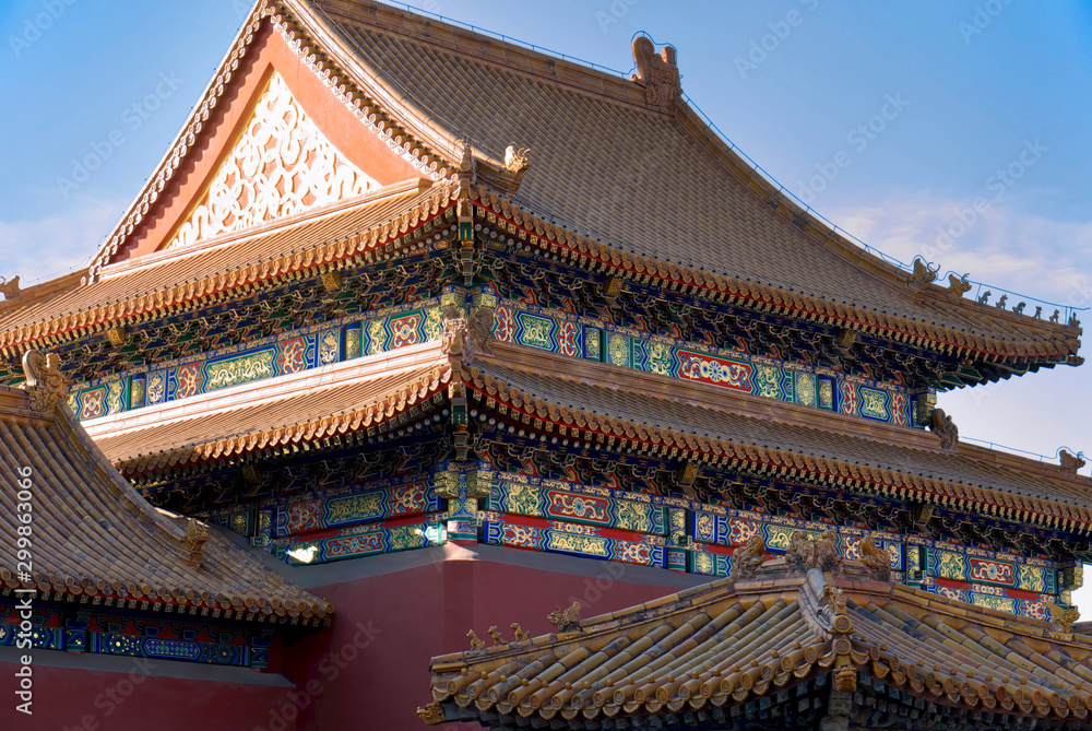 curved roofs in traditional Chinese style with figures on the blue sky background. The Imperial Palace in Beijing curved roofs in traditional Chinese style with figures on the blue sky background. The Imperial Palace in Beijing