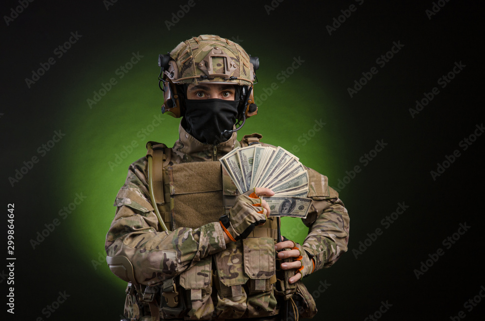 a male soldier in military clothes with a weapon on a dark background with money a male soldier in military clothes with a weapon on a dark background with money