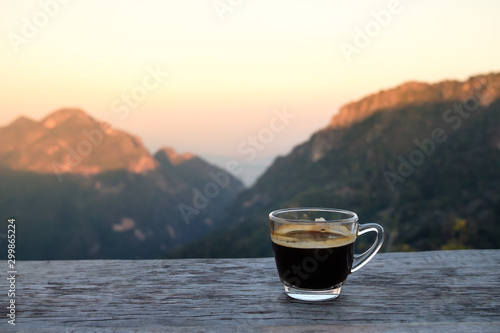 Hot americano coffee on wooden table with mountain view