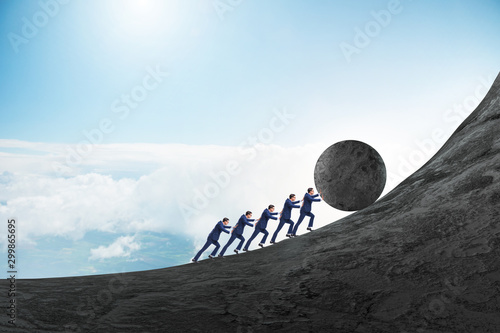 Fotografie Team of people pushing stone uphill