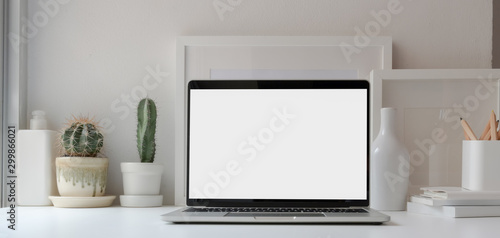 Open blank screen laptop computer in minimal workspace with cactus pots