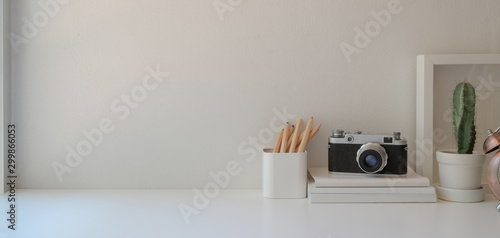 Minimal workplace with copy space and office supplies on white wooden table and white wall