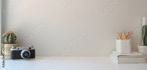 Minimal workplace with copy space and office supplies on white wooden table and white wall photo