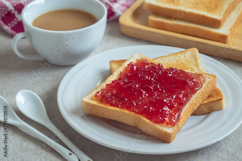 Toast bread with strawberry jam on plate and coffee cup.