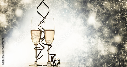 two champagne glasses with ribbons against holiday lights and fireworks - New Year celebrations