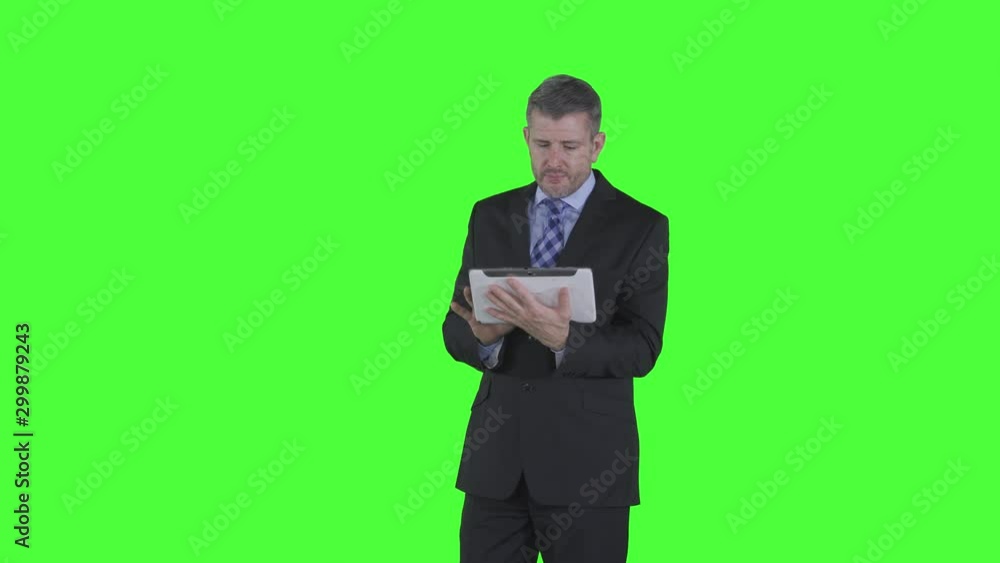 Caucasian businessman using a digital tablet while standing in the studio. Shot in 4k resolution with green screen background Caucasian businessman using a digital tablet while standing in the studio. Shot in 4k resolution with green screen background