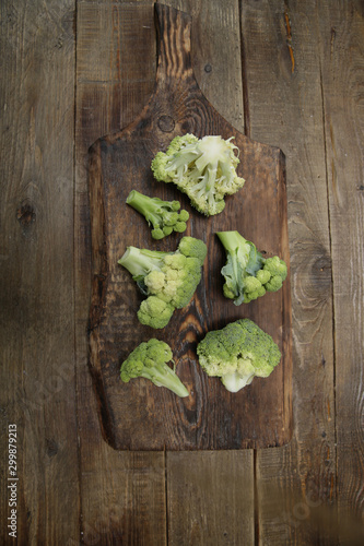 Organic fresh raw broccoli isolated on a wooden rustic board. Healthy food concept. Vegan. Top view. Flat lay. With copy space for text. Vertical photo. Green food background, poster, pattern.