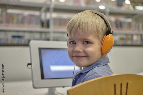 Wallpaper Mural Elementary school boy in library, using touchscreen computer for education, looking into camera and smile. Concept: technology and modern learning environment Torontodigital.ca