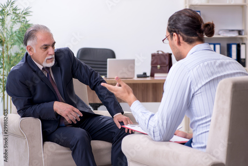 Old man visiting young male doctor psychologist