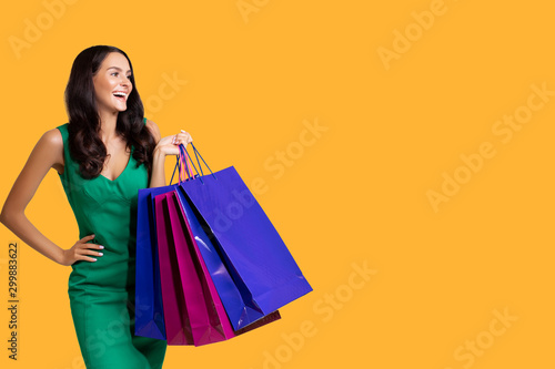 Shopping Girl with purchases. colored bags. Photo Charming Girl attractive joyful girl having just ended up Shopping and being overjoyed and cheerful. isolated. Orange Background. color background 
