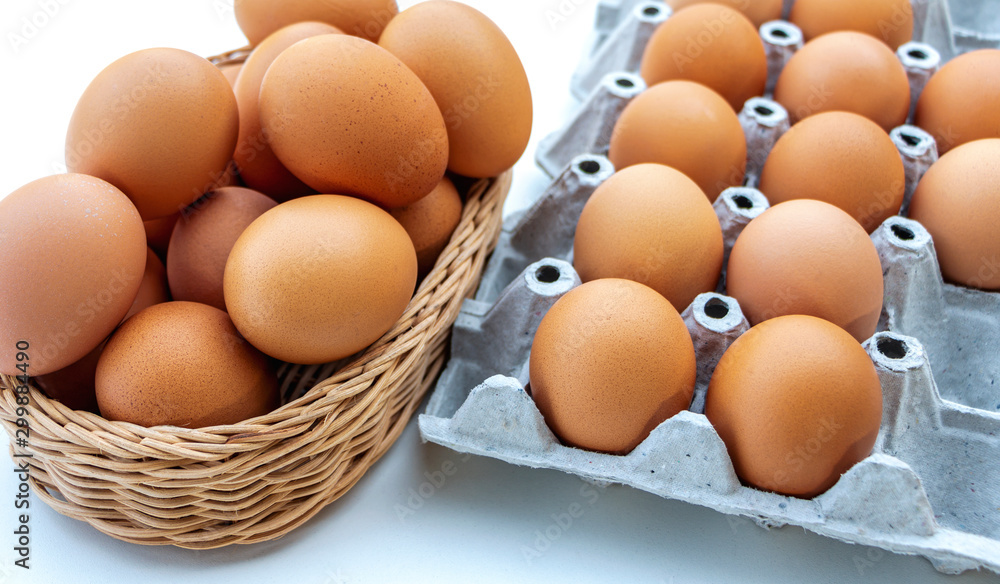 Fresh chicken eggs are placed in recyclable paper trays and basket in the kitchen. Fresh chicken eggs are placed in recyclable paper trays and basket in the kitchen.