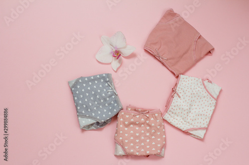 Beautiful women's cotton panties on pink background with orchid bud. © Vitalii M