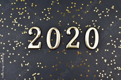 2020 is written in golden numbers on a black background strewn with gold stars.