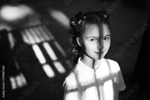 cute little thoughtful girl standing at the night playground. shadows from gungle gym falling on her face and body. black and white photo photo