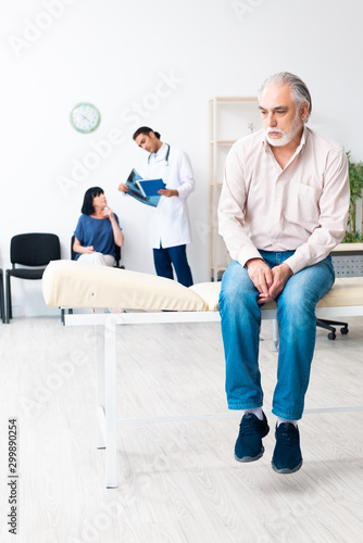 Old couple visiting young male doctor