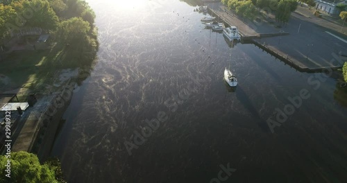 Aerial drone scene of foggy sunrise at river discovering Mercedes city at backgorund. From top to front view of cityscape. Sailboats, boats moorings. Uruguay photo