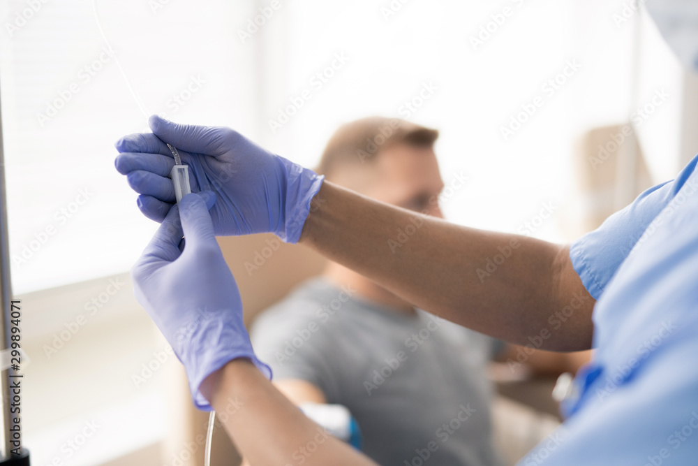 Hands of gloved doctor holding part of dropper with medicine for one of patients - obrazy, fototapety, plakaty 