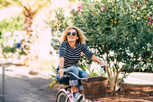 Cheerful young happy people enjoying the outdoor leisure activity riding a bike and smiling for happiness - young caucasian beautiful curly lady smile and enjoy the healthy ilfestyle photo