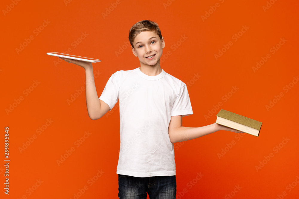 Teenager comparing digital tablet and printed book Teenager comparing digital tablet and printed book