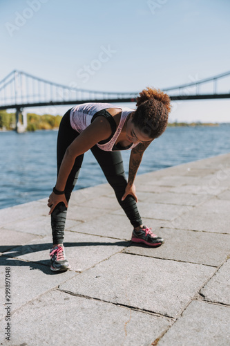 Sporty Afro American lady doing morning exercise by the river